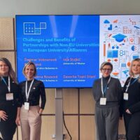 Four women posing in front of a screen for a group picture. The screen shows the logo of the CEEDUCON Conference, the topic of the workshop, and the moderators' names and universities.