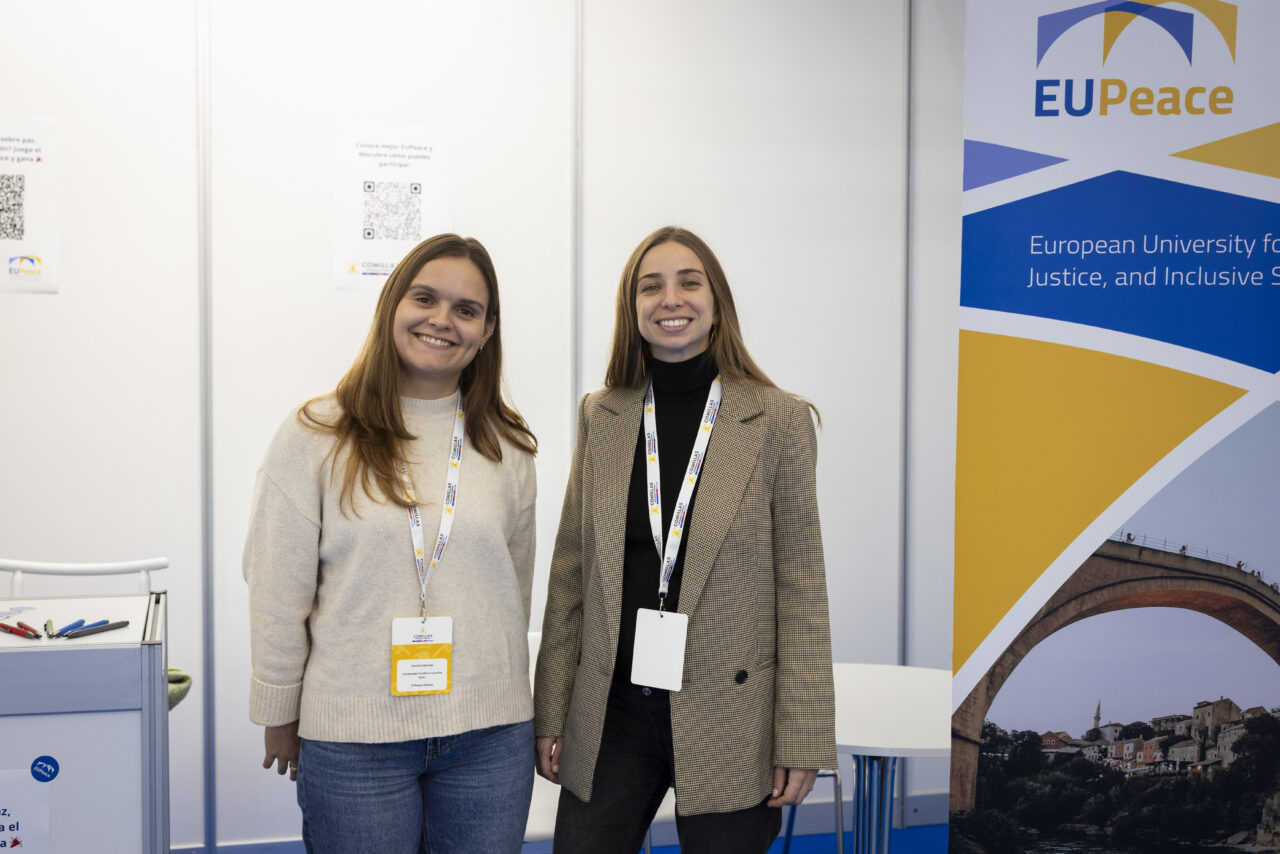 Two EUPeace representatives stand at their booth during the International Fair at Comillas Pontifical University on October 29, 2025.