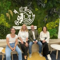 Four relaxed professors, three female, one male, sitting in front of Comillas' logo after debating their European Track Course "Exile and Migration in World Literature".