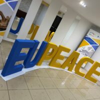 Large 3D letters spelling "EUPeace" in blue and yellow displayed at the EUPeace Autumn Meetings 2025 in Pilsen, Czechia, with banners showing the alliance’s mission and partner universities.