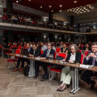 An audience in big room listens to the keynote speeches