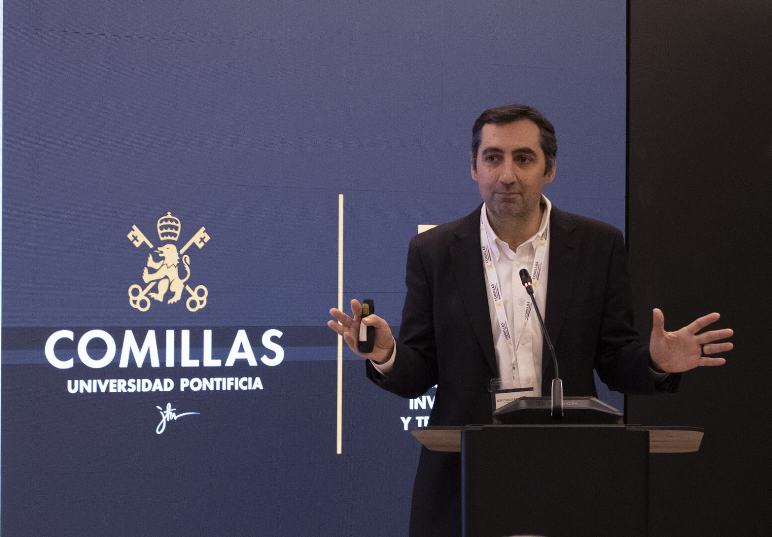 A speaker addresses the audience from the podium at Universidad Pontificia Comillas.