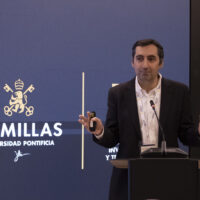 A speaker addresses the audience from the podium at Universidad Pontificia Comillas.