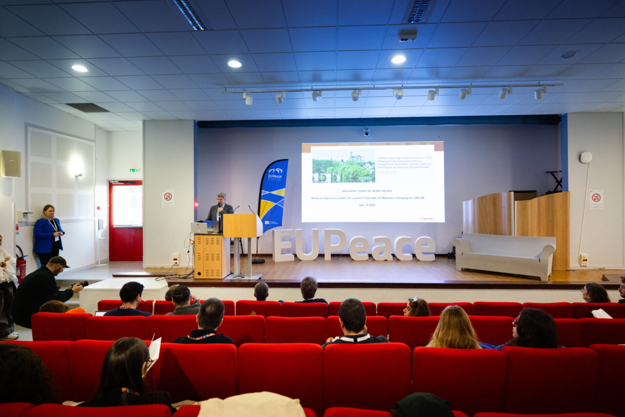 A man standing on the left side of a stage giving the keynote speech for the conference.