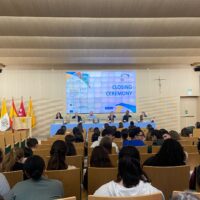 Audience seated in a university lecture hall facing a panel of speakers during the EUPeace closing ceremony, with event branding displayed on a large screen.