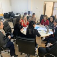 A group of professionals seated around a table discussing coordination and collaboration during a working group meeting